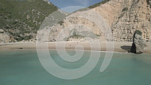 Drone shot over ribeiro do cavalo beach with cliffs and rocks on a sunny day