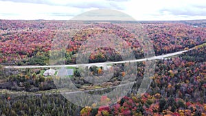 Drone shot of a road in the middle of colorful trees landscape at fall season