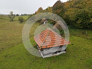 Drone shot of a rural wooden cottage in a large green field in Sjenica, Serbia photo