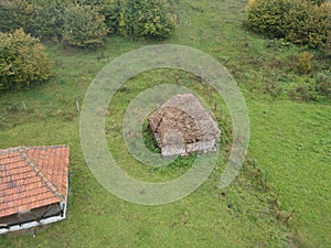 Drone shot of rural wooden cottages in a large green field in Sjenica, Serbia photo