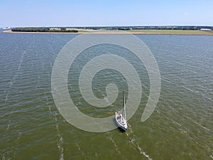 Drone shot of a sailboat anchored under typical Dutch blue sky