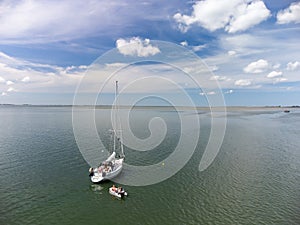 Drone shot of a sailboat anchored under typical Dutch blue sky