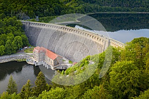 Drone shot of stone river dam at reservoir with flowing water, hydroelectricity power station in mountains