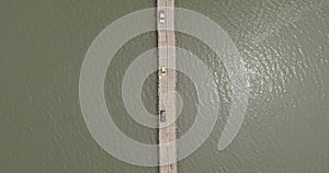 Drone shot of vehicles crossing bamboo bridge over a river