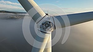 Drone shot wind turbine during sunrise dense morning fog. Close-up Wind turbines. Windmills producing clean green energy.