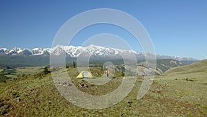 Drone shot. Woman tourist travel vacation. Traveling mountains, freedom and active lifestyle concept. Yellow tent. Young