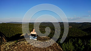 Drone shot of a young charming freelance woman with a laptop in her hands looking ahead enjoying a beautiful view in the