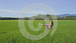 Drone Shows Girl Doing Yoga against Green Hills Clear Sky