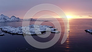 Drone sideway move video of fishing boat sailing on fishing during sunrise in arctic lofoten islands. sunlight and snow mountains.