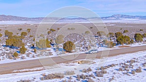 DRONE: Silver SUV drives along a scenic interstate crossing snowy Montana.