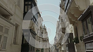 Drone smooth flying back through beautiful old street,Valletta,Malta . Old, vintage windows, balconies. - 4K