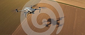 The drone soaring over agricultural fields casting a distinctive shadow..AI generated image