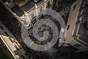 The drone soars high above the crowd, capturing a bird's eye view of the throng of people gathered below. Ai