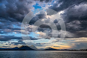 DRONE: Stunning shot of dark clouds gathering above Lago Di Maggiore at sunset.