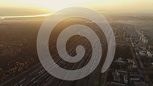 A drone takes off over a railway station. Aerial top view. Railway sorting station at sunset. Many wagons at the cargo