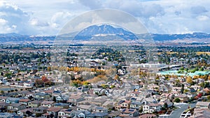 A drone telephoto photo of a community in northern California with a large mountain in the background with a clouded sky