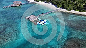 Drone top down view of a Seaplane. Tropical atoll island in Maldives with coral reef and turquoise sea water. Touristic