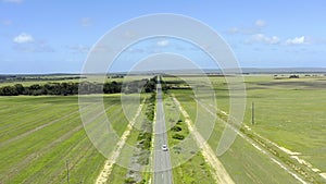 Drone, travel and a car on a road in the countryside for freedom or adventure on a green landscape. Earth, sky and