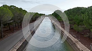 Drone traveling through the Tajo - Segura water transfer channel in the province of Albacete, Spain, among a lush pine forest