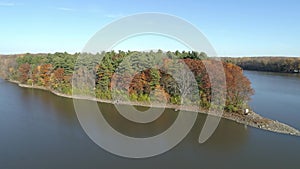 Drone video flying high above the river, towards a calm river in the Fall, with a blue clear sky