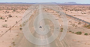 Drone video of a four-wheel drive vehicle driving on a gravel road in a desert area in Namibia