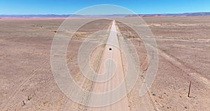 Drone video of a moving vehicle on a lonely gravel road through the desert