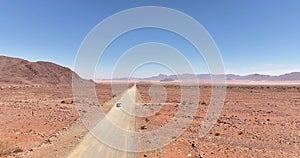 Drone video of a moving vehicle on a lonely gravel road through the desert