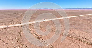 Drone video of a moving vehicle on a lonely gravel road through the desert