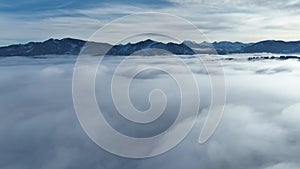 Drone video in winter with fog in the valley in front of the mountains