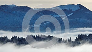 Drone video in winter with fog in a valley in front of the mountains