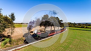 Drone View of an Antique Steam Passenger Train, Rounding a Curve, Blowing Smoke