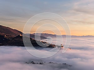 Drone view of Assisi Umbria Italy above a sea of fog at sunset