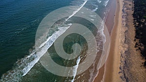 Drone view of beautiful seamless  footage of Goa sea waves breaking on sandy coastline. Golden beach with deep blue ocean water