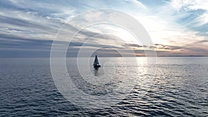 Drone view of a boat sailing across the blue clear sea or ocean. Aerial view of luxury floating boat on blue sea