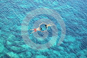 Drone view of couple snorkeling in blue sea water