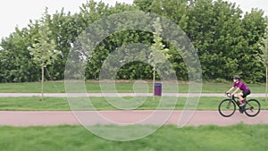 Drone view of female cyclist cycling on bike. Woman in helmet and cycling clothes is training on bicycle, doing cardio exercises o