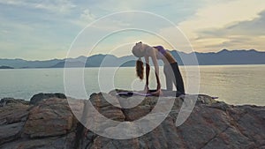 Drone view girl does yoga against sunrise hills on sea coast