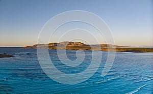 Drone view of Isola Piana by La Pelosa Beach, Sardinia. Well-preserved ruins of Torre di Punta Imbarcatogio, a defensive and