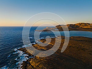 Drone view of Isola Piana by La Pelosa Beach, Sardinia. Well-preserved ruins of Torre di Punta Imbarcatogio, a defensive and