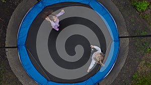 Drone view of jumping girls from above. Little girls jump on a trampoline in the yard.