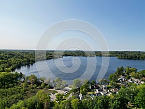 Drone view of Lake Attitash surrounded by greenery on a sunny day in Massachusetts