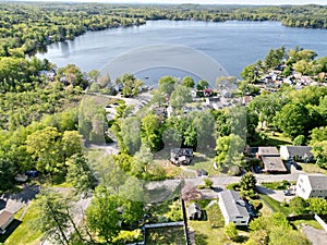 Drone view of Lake Attitash surrounded by greenery on a sunny day in Massachusetts