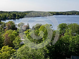 Drone view of Lake Attitash surrounded by greenery on a sunny day in Massachusetts