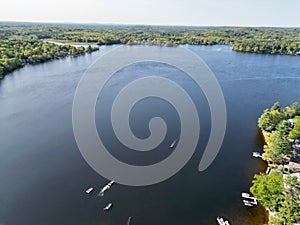 Drone view of Lake Attitash surrounded by greenery on a sunny day in Massachusetts