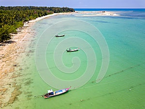 Drone view of longtail boats moored off a tropical sandy beach in Khao Lak, Thailand