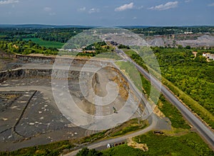 Drone view of opencast mining quarry in the middle of the forest landscape