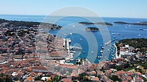 Drone view of red-roofed buildings in Hvar with ships and boats in the Adriatic Sea in the backdrop