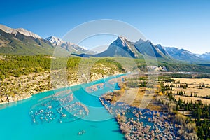 A drone view of the river in the mountains valley. An aerial view of an autumn forest. Winding river among the trees.