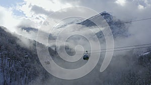 Drone view ski lift moving over fogy woodland on winter resort. Aerial landscape ski elevator transporting sportsmen between snowy