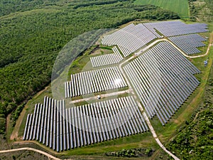 drone view of a solar power station next to a forest during summer. Renewable energy meets nature in action